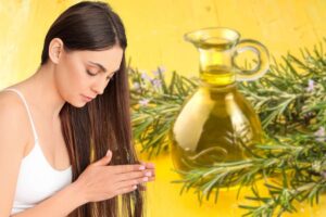 donna con mani nei capelli ed olio di rosmarino