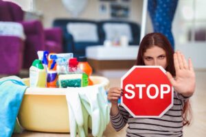 donna che fa le pulizie e un'altra con segnale di stop tra le mani
