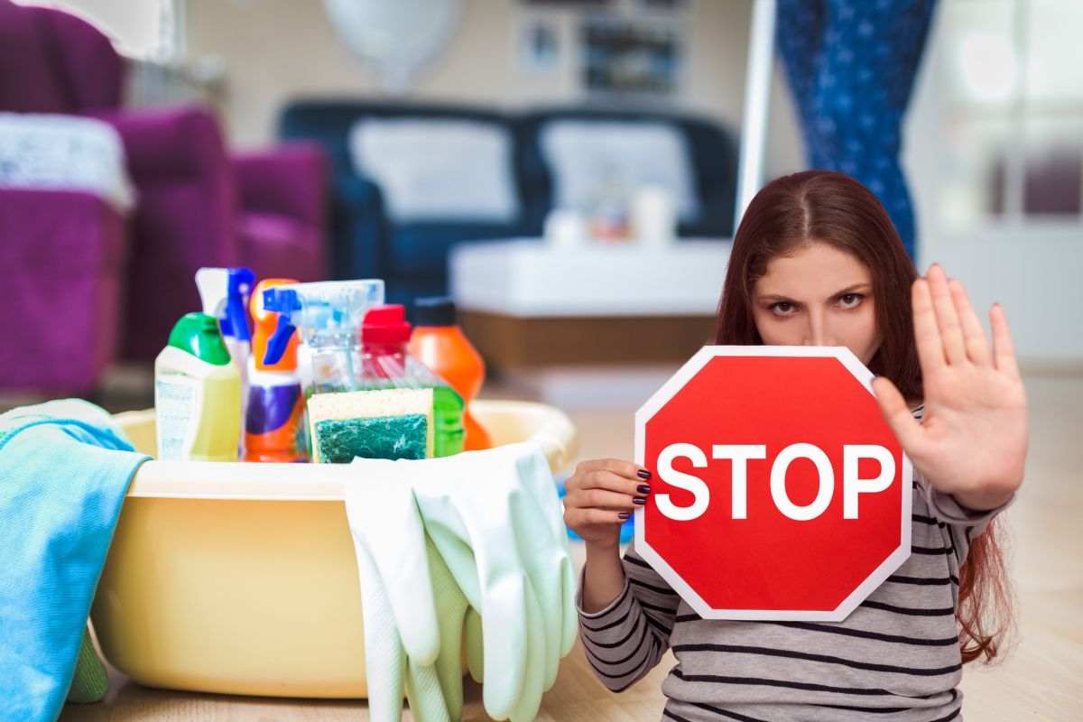 donna che fa le pulizie e un'altra con segnale di stop tra le mani